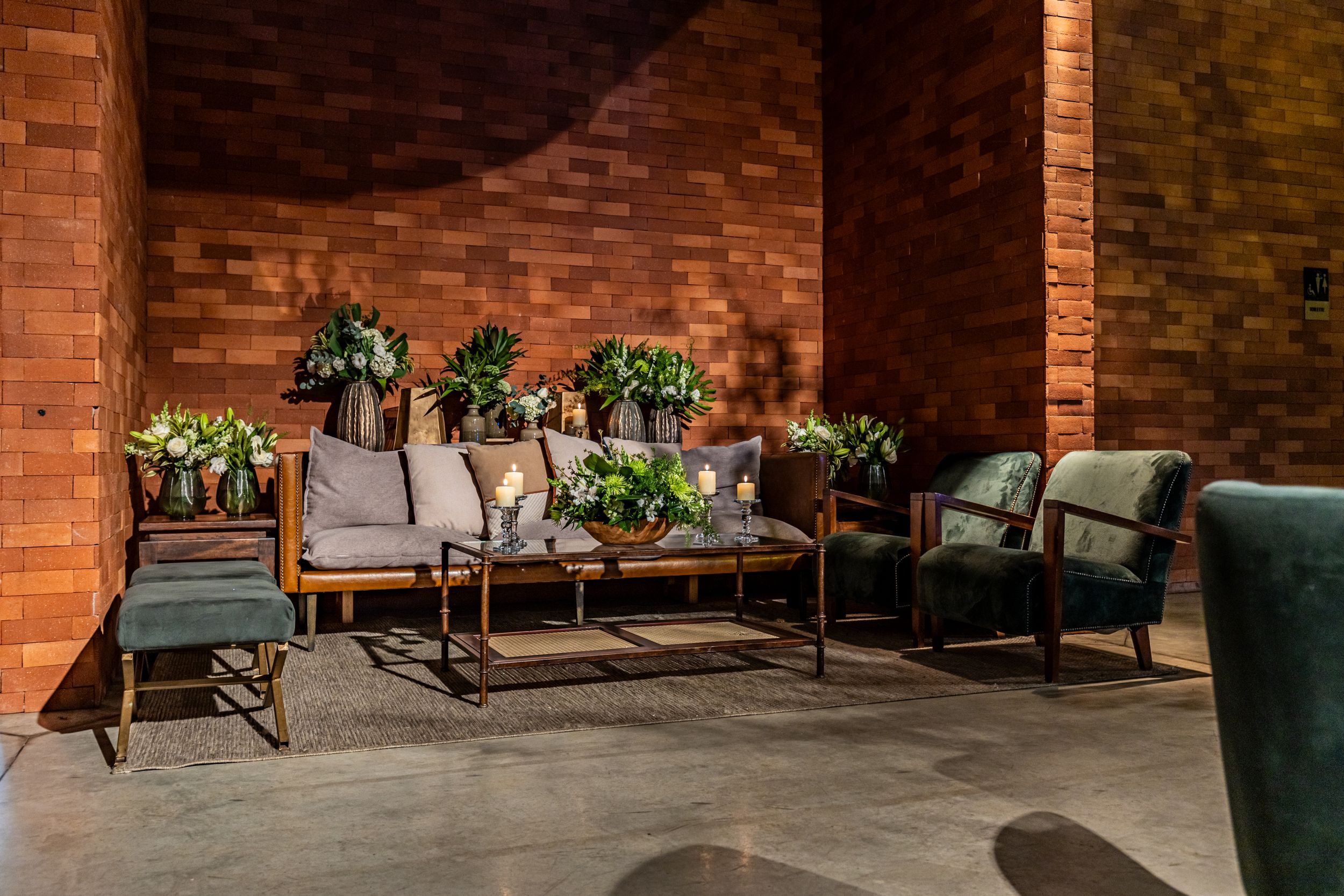 Green velvet armchairs and a coffee table in a warm, plant-filled lounge